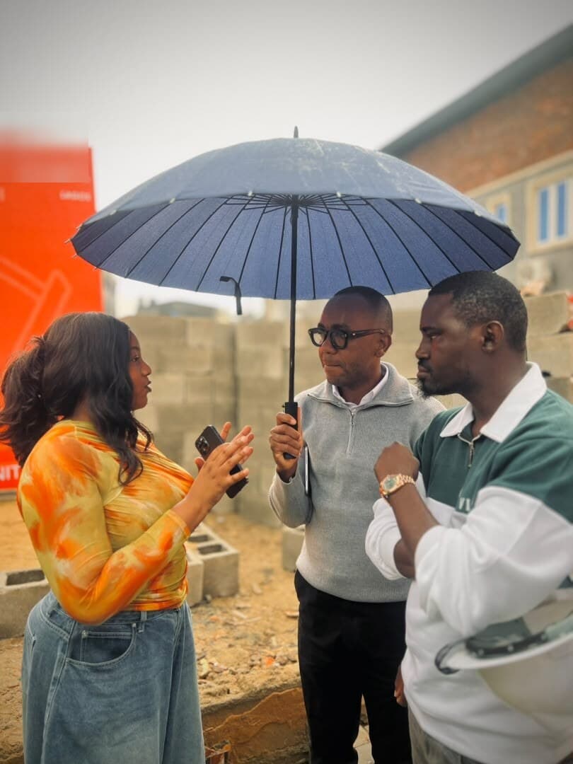 The team talking on site under umbrellas at the groundbreaking